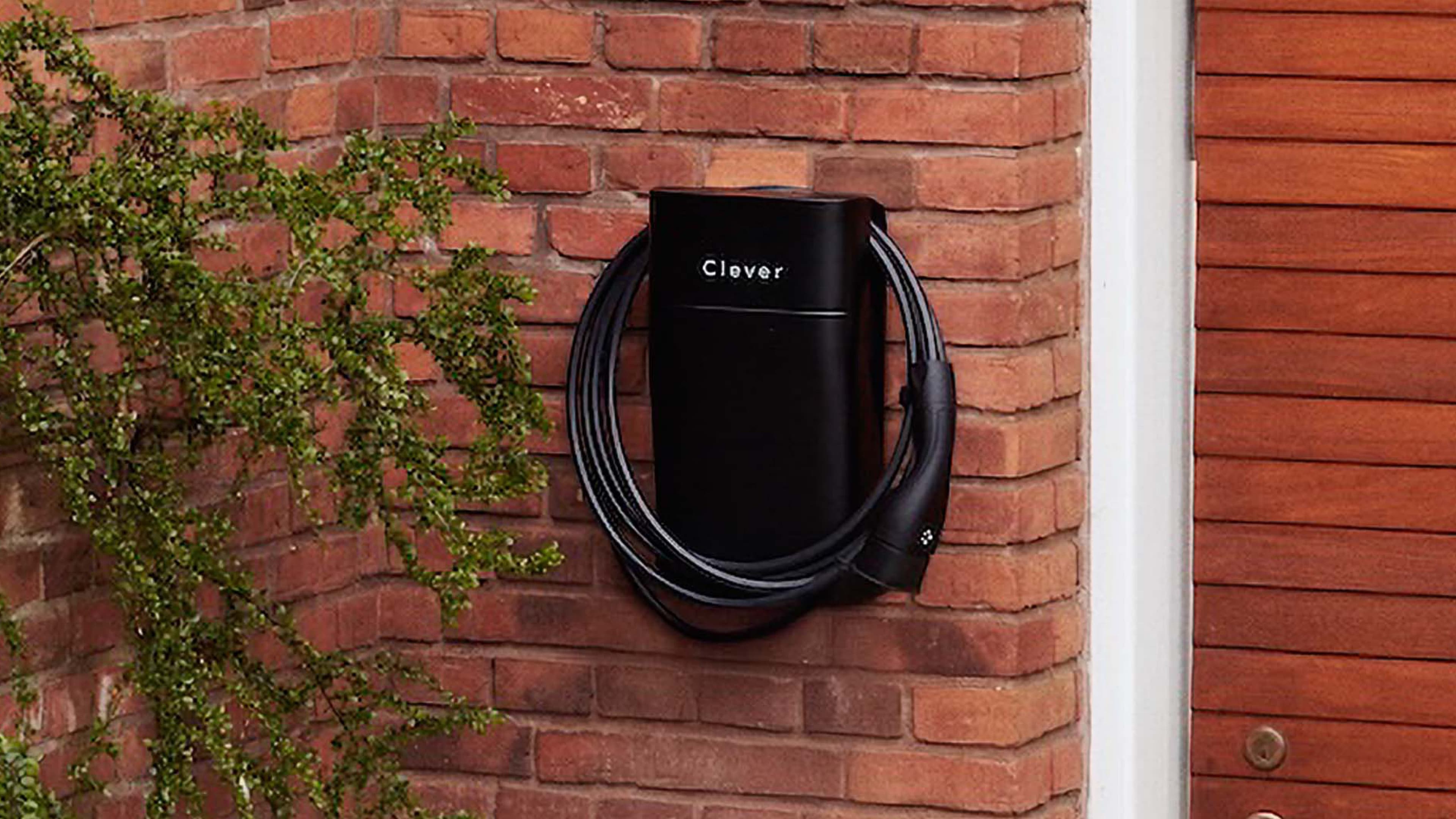 Clever ladeboks og kabel ophængt på en rød murstensmur, og en plante der kravler opad væggen.