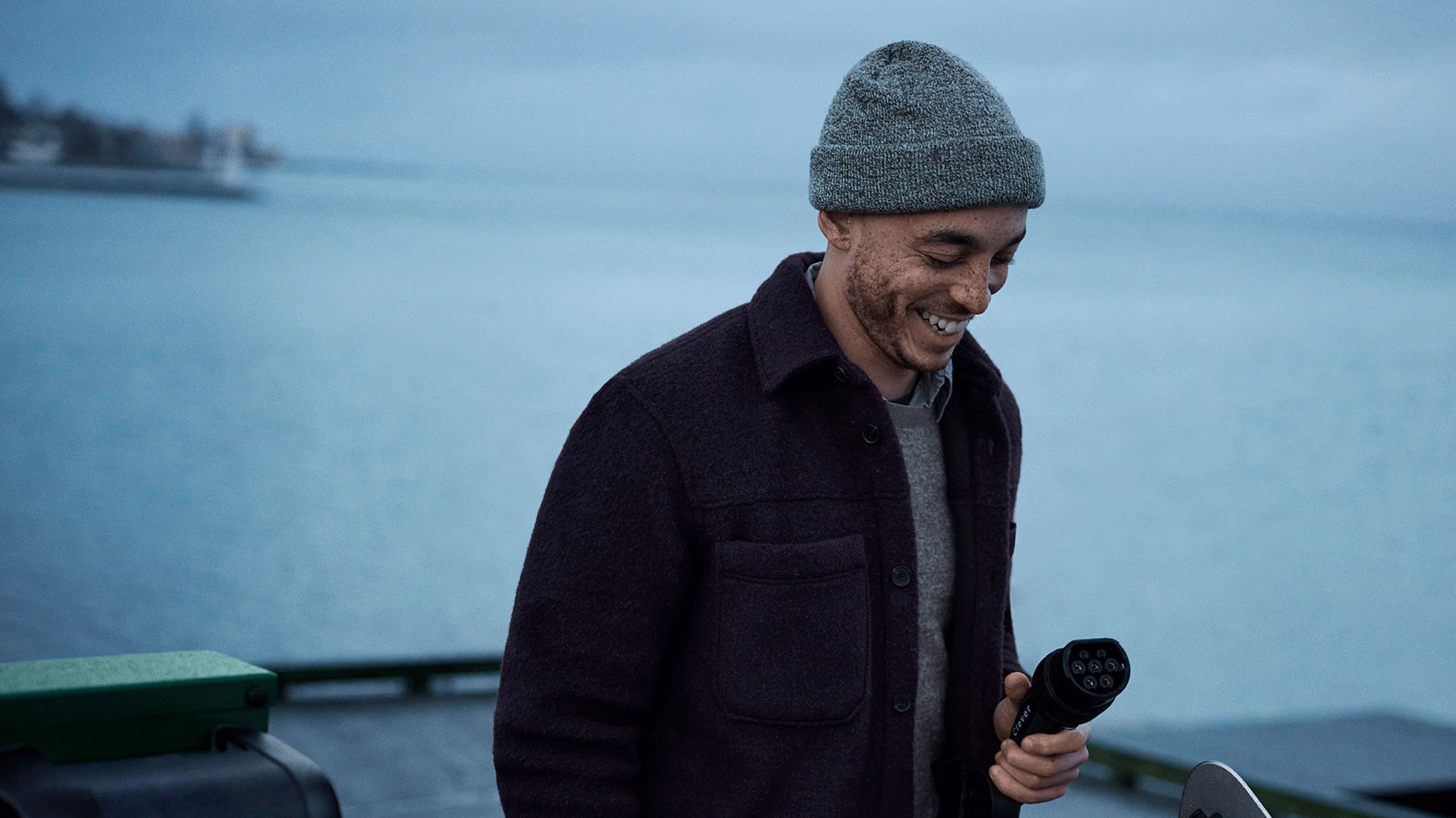 En smilende mand holder et Clever opladerstik