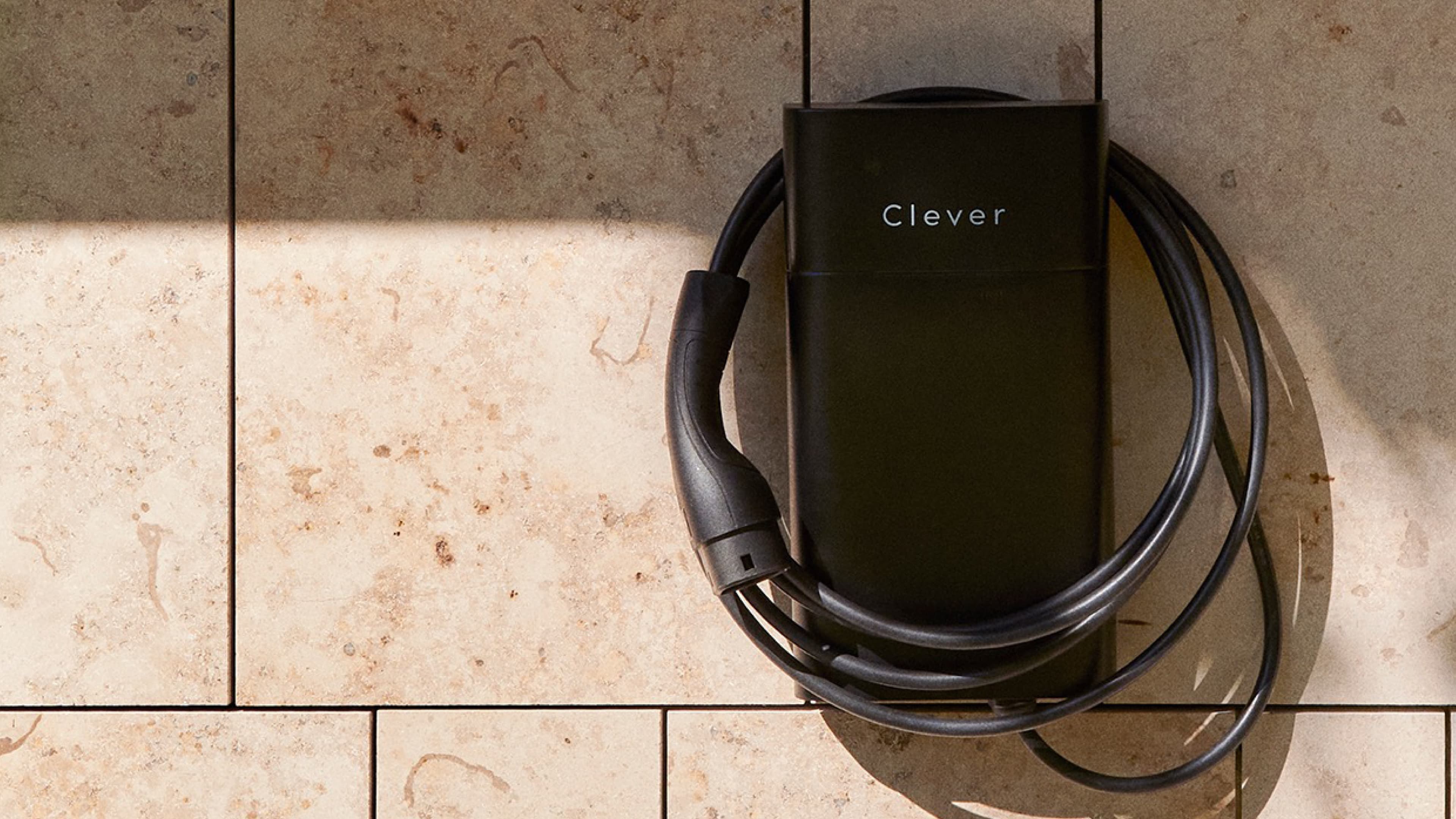 Clever ladeboks og kabel ophængt på en væg med beige marmor klinker